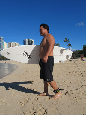 Surfer models a shark deterrent device, the Electronic Shark Defense System, attached to his ankle and surfboard at a Honolulu beach.